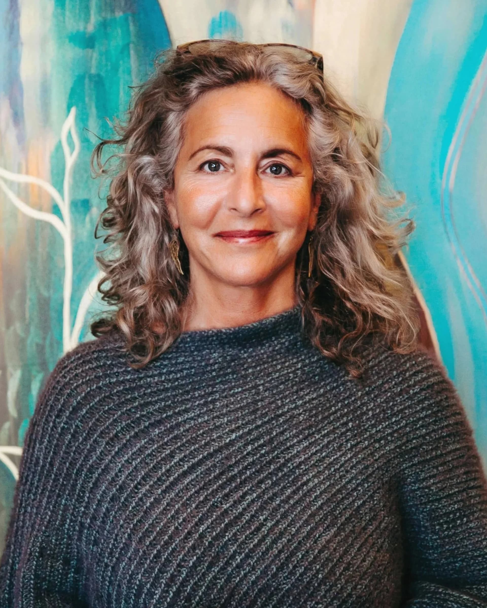 Heidi Feinstein, founder of Rooted Vision Studio, with shoulder-length curly gray hair in a dark textured sweater